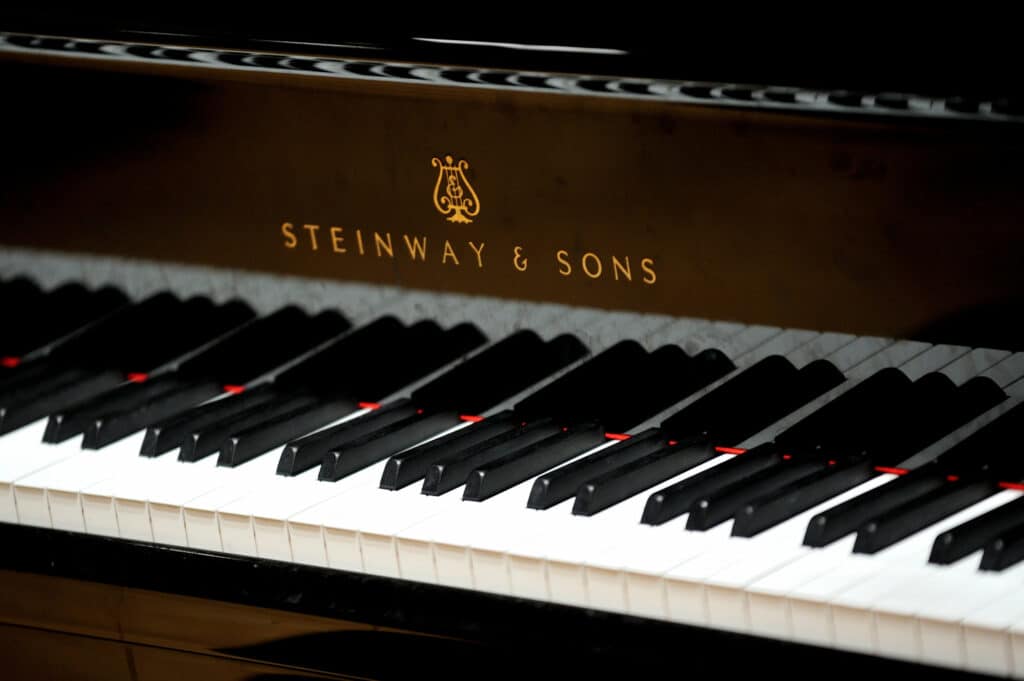 Clavier noir de piano Steinway & Sons. Logo lyre doré et nom "STEINWAY & SONS" sur la plaque. Touches blanches et noires.