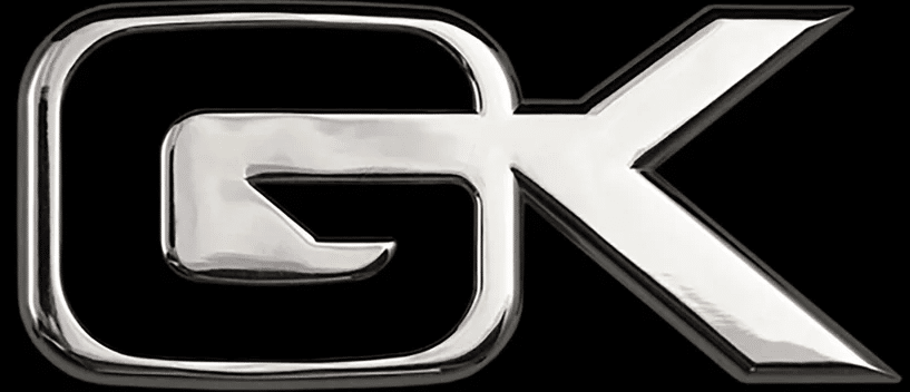 Emblème chromé brillant avec les lettres majuscules stylisées 'GK' sur un fond noir. Le logo a un aspect métallique poli.